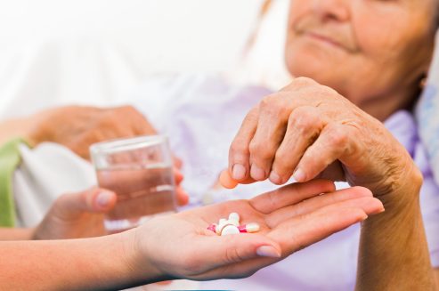 Homecare nurse helping elderly lady to take her daily medicine.